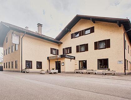 Traditionelles bayerisches Gasthaus mit beiger Fassade und dunklen Holzläden